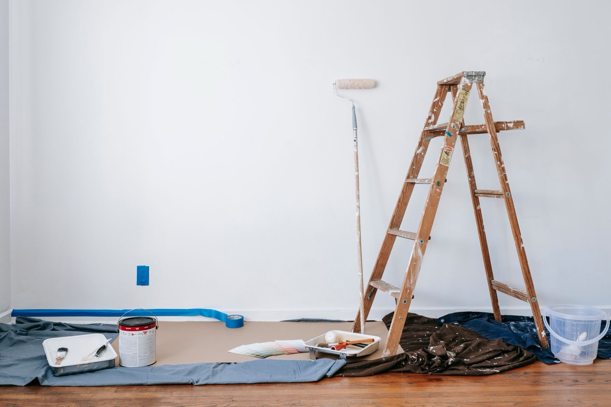 Chantier de peinture préparé : sols bâchés, escabeau et nuanciers